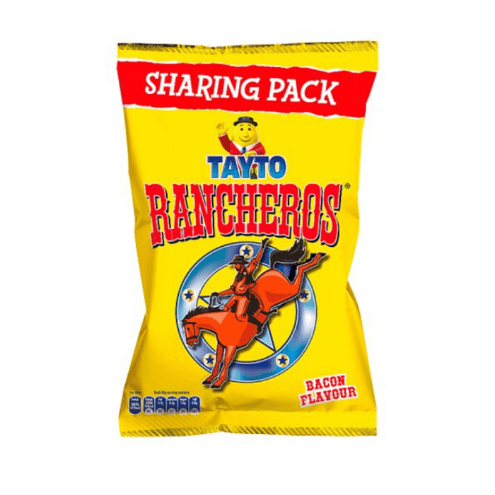 A yellow Tayto Rancheros Sharing Bag (Box of 12 x 100g), featuring a cowboy on horseback with a blue and yellow star, brings classic Irish bacon flavour snacks from the Tayto brand—perfect for sharing.