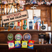 Wooden pub bar with assorted beer taps, pints, and a sign reading "Netcrisps Home Bar Collection," with four packets of crisps displayed in front (Bacon fries, KP Salted Nuts, Scampi Fries and Tayto Cheese and Onion)